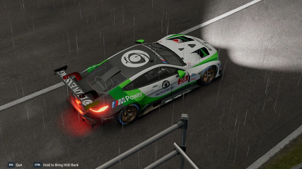 Project Motor Racing: en grön, vit och svart BMW M-racerbil med nummer 28 står stilla på en regnvåt bana, sedd uppifrån och bakifrån, med lysande bromsljus.