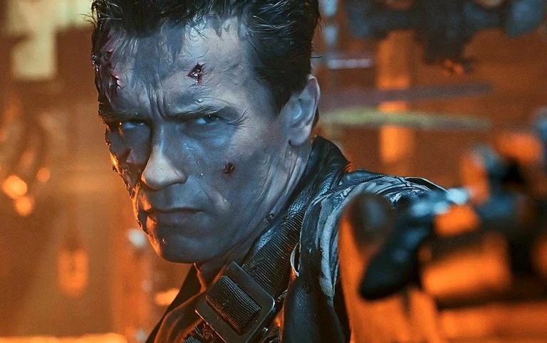 Närbild på en man med allvarlig blick och skadat, blodigt ansikte i läderjacka som sträcker ut armen mot kameran i en dunkel industrimiljö med orange sken, scen ur Terminator 2: Judgment Day.