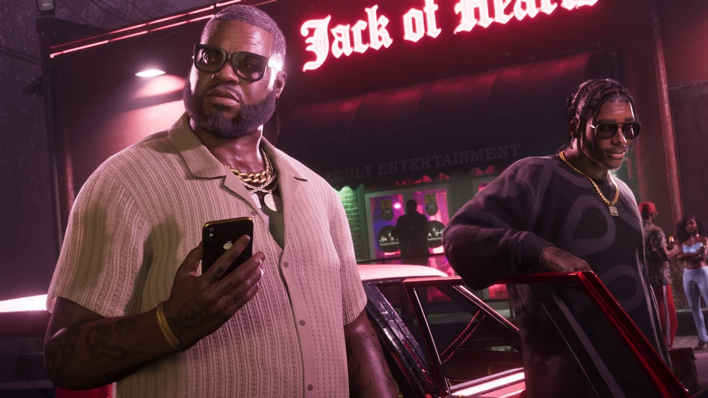 Två män i solglasögon och guldkedjor framför neonskylten Jack of Hearts i Grand Theft Auto VI. Den ene håller en mobil, den andre lutar sig mot en röd bil.