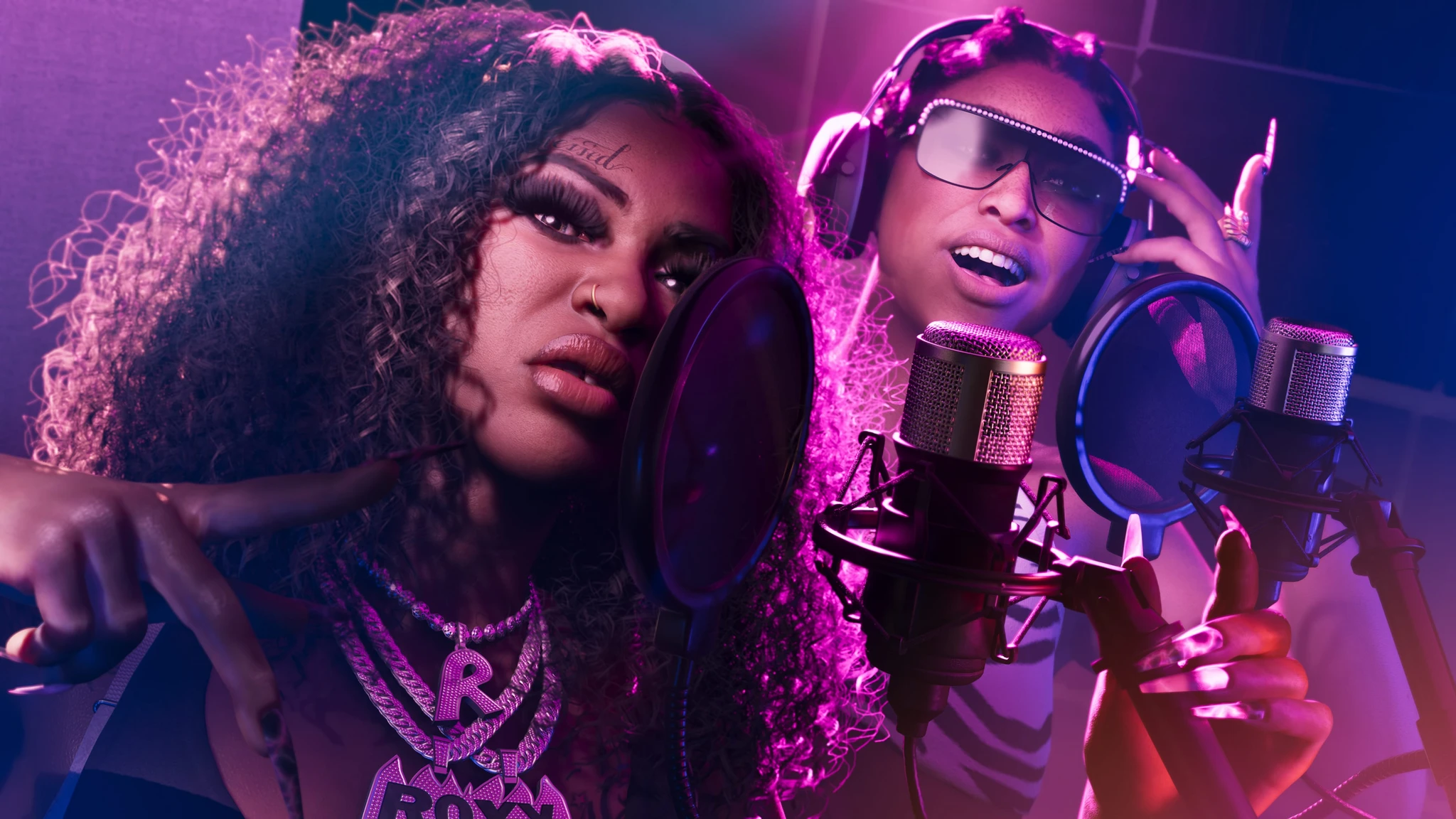 Två kvinnor i en inspelningsstudio med lila och rosa belysning står framför kondensatormikrofoner med popfilter.