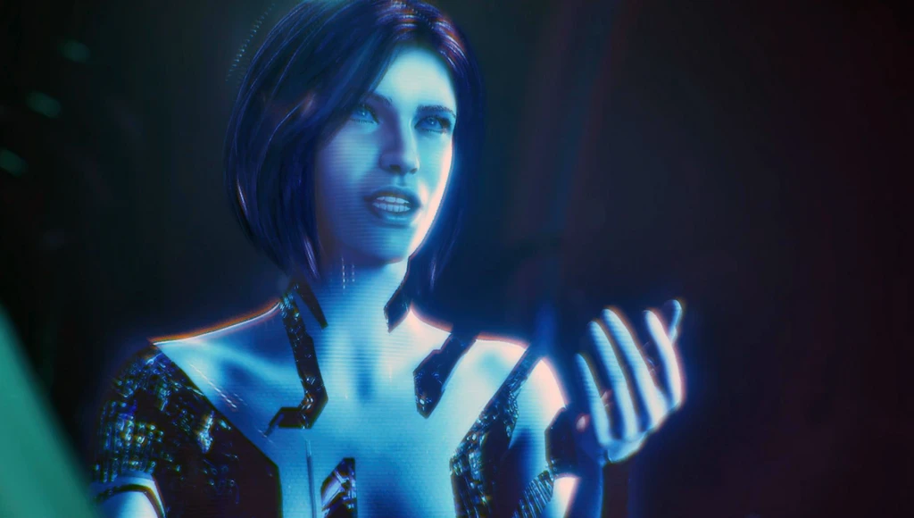 Den blå, självlysande AI-gestalten Cortana i Halo: Campaign Evolved talar och håller upp handen, som om hon visar något, mot en mörk bakgrund.