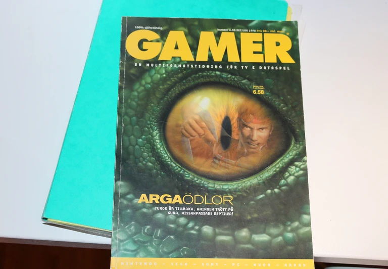 Omslaget till speltidningen Gamer från dec/jan 1998 med ett grönt reptilöga i närbild, där en krigare med pannband syns i pupillen. Rubriken lyder "Arga ödlor".