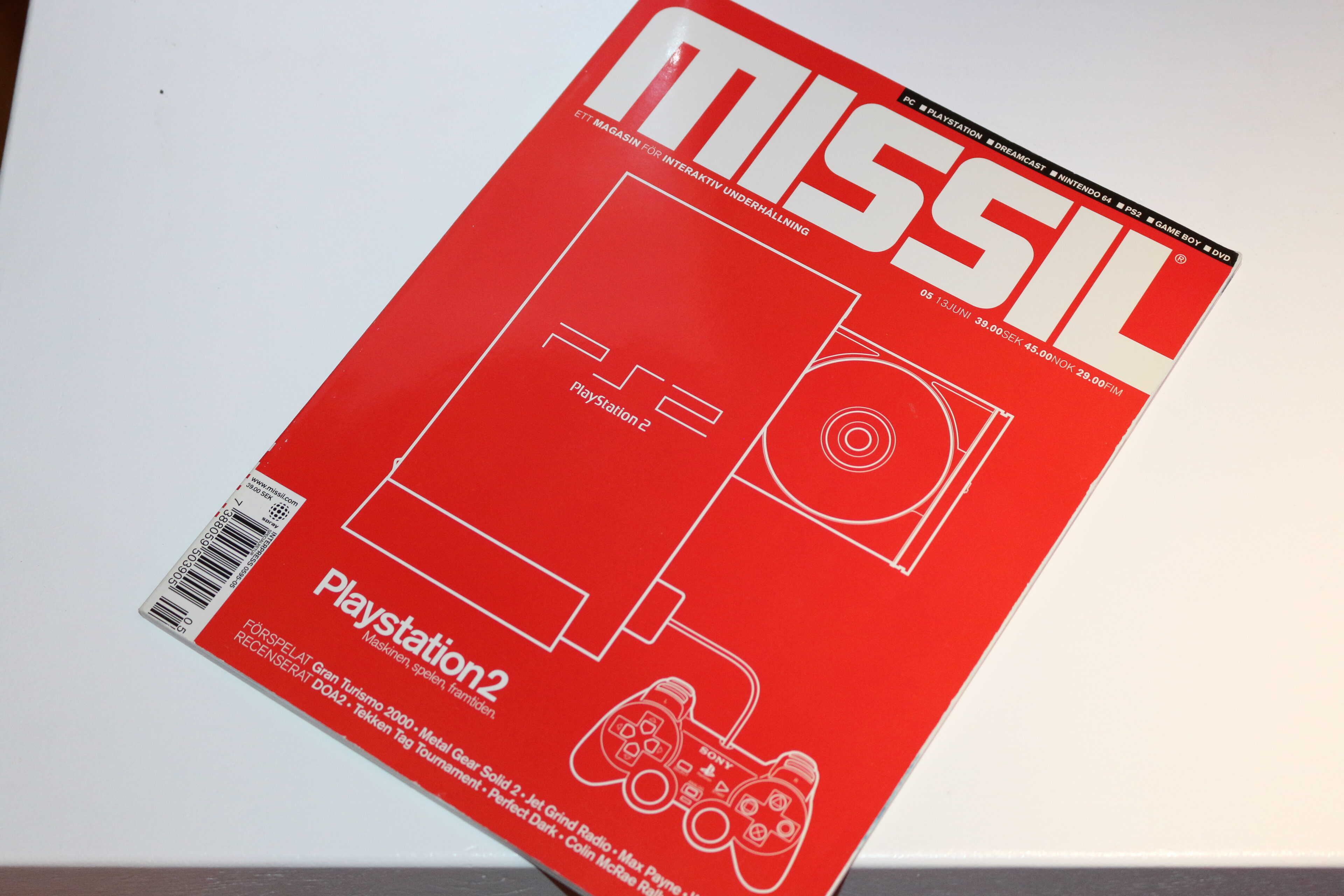 Omslaget till speltidningen MISSIL med rött tema och en linjeteckning av Playstation 2-konsolen och en handkontroll, med rubriken Playstation2.