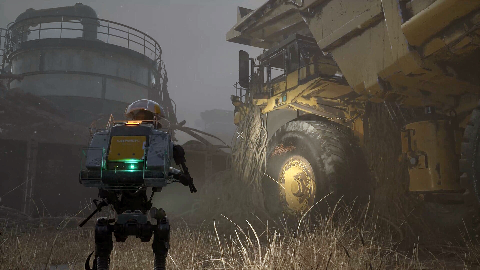 En liten tvåbent robot med ryggsäck och grönt ljus står i dimman framför en enorm övergiven gruvlastbil överväxt med rötter, intill en rostig silo.