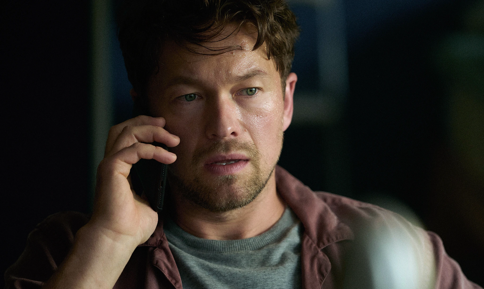 Thomas Berg, spelad av Jakob Oftebro, pratar i mobiltelefon med allvarlig och spänd min i ett mörkt rum i Netflix-serien Blodsoffer.