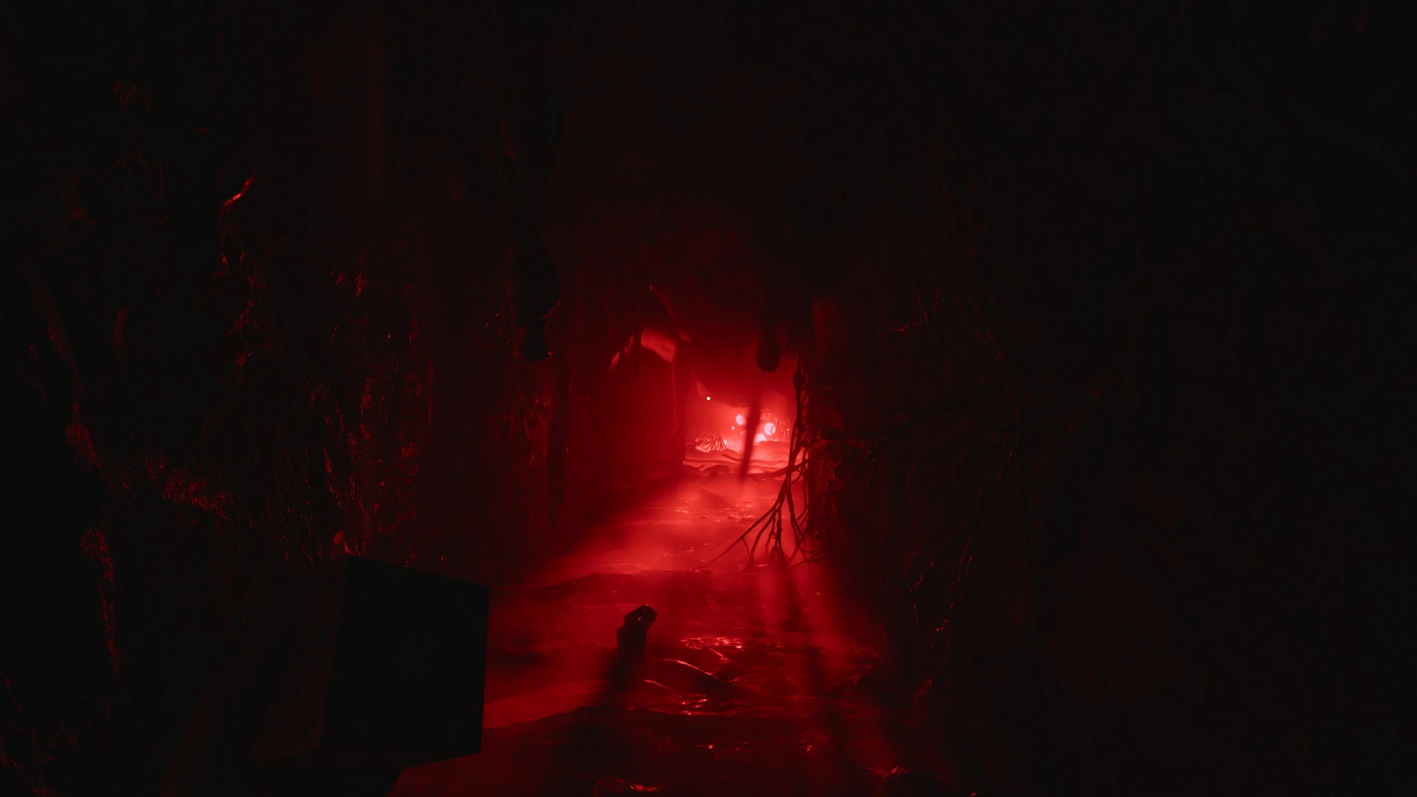 Mörk, rödbelyst korridor med grenar som hänger från väggen och ett glödande sken längre bort, från skräckspelet Clive Barker's Hellraiser: Revival.