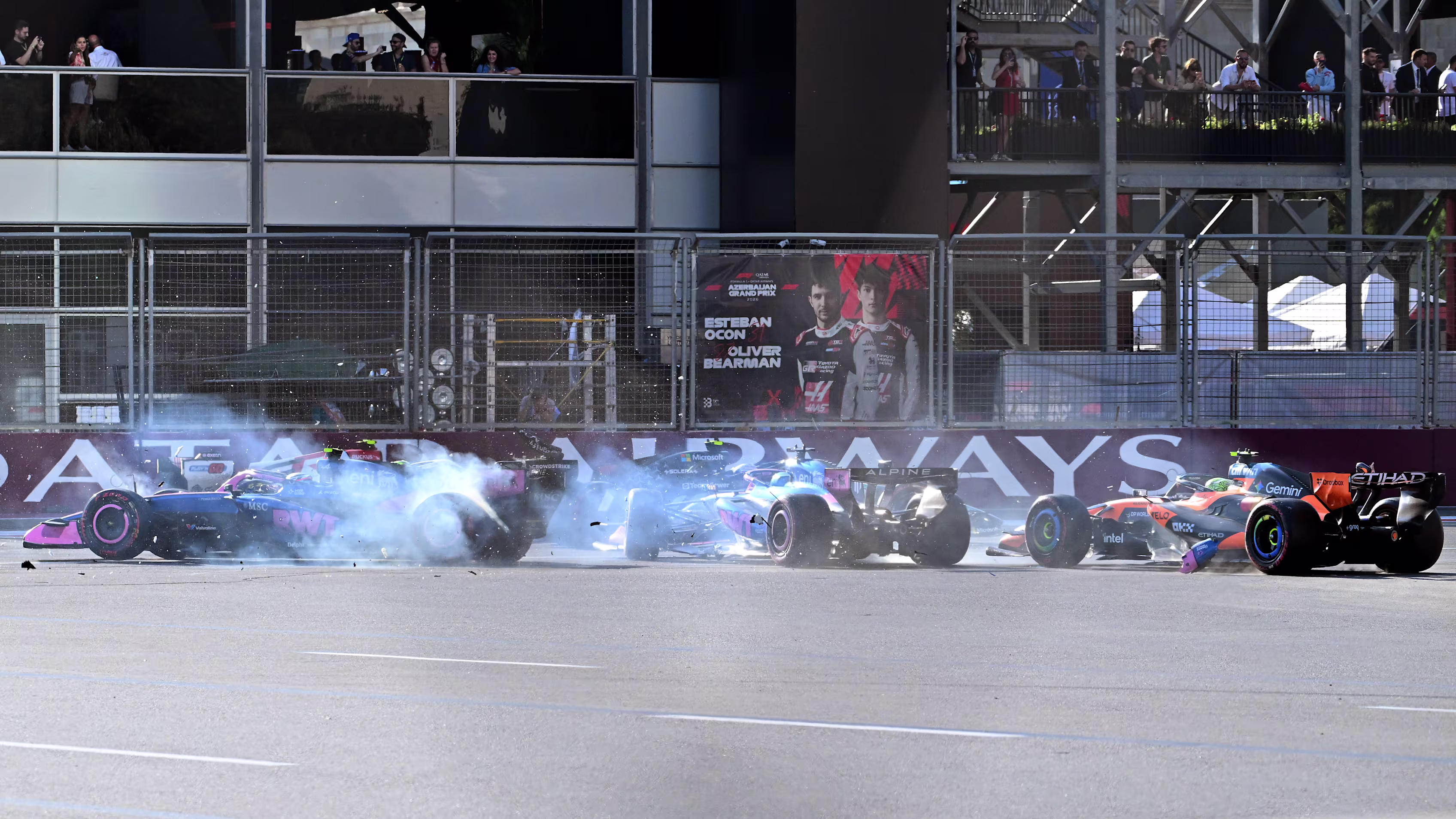 Flera Formel 1-bilar kolliderar vid en bana med rök från däcken, medan åskådare tittar från läktare i bakgrunden under Azerbajdzjans Grand Prix.