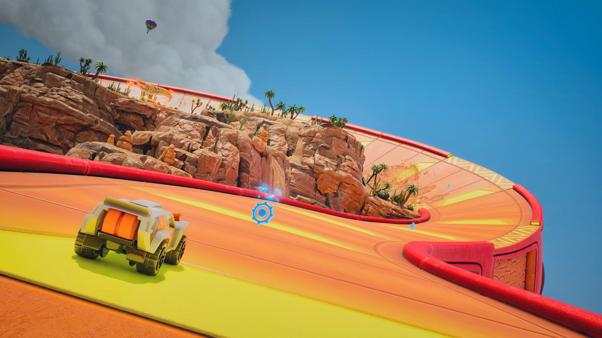 I Hot Wheels Infinite Rush kör en terrängbil på en orange racerbana med röda kanter som svänger runt en klippig ökenmiljö med palmer under blå himmel.