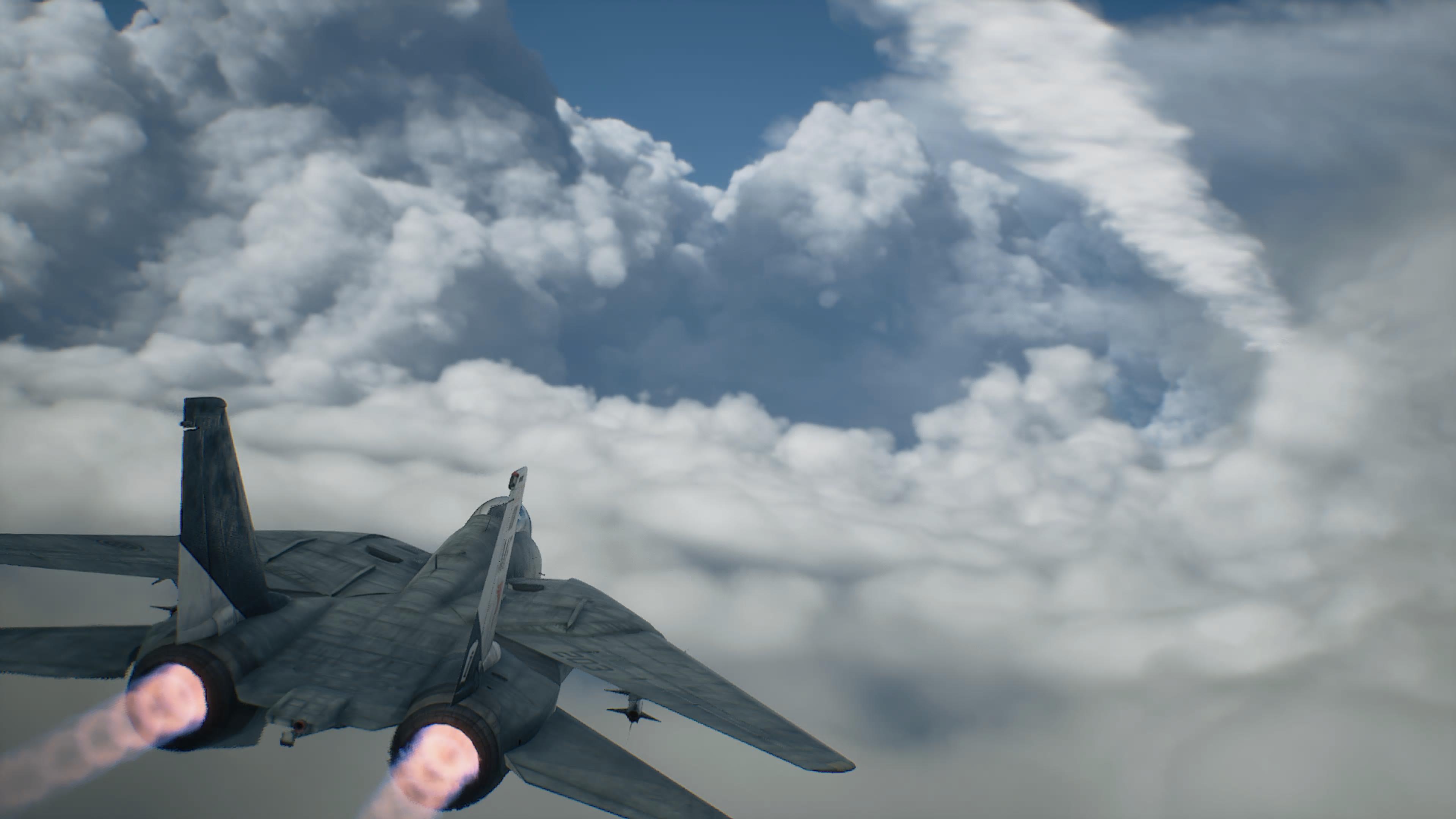 Ett stridsflygplan med glödande efterbrännare sett bakifrån medan det flyger mot en vägg av stora moln mot blå himmel i Ace Combat 8: Wings of Theve.
