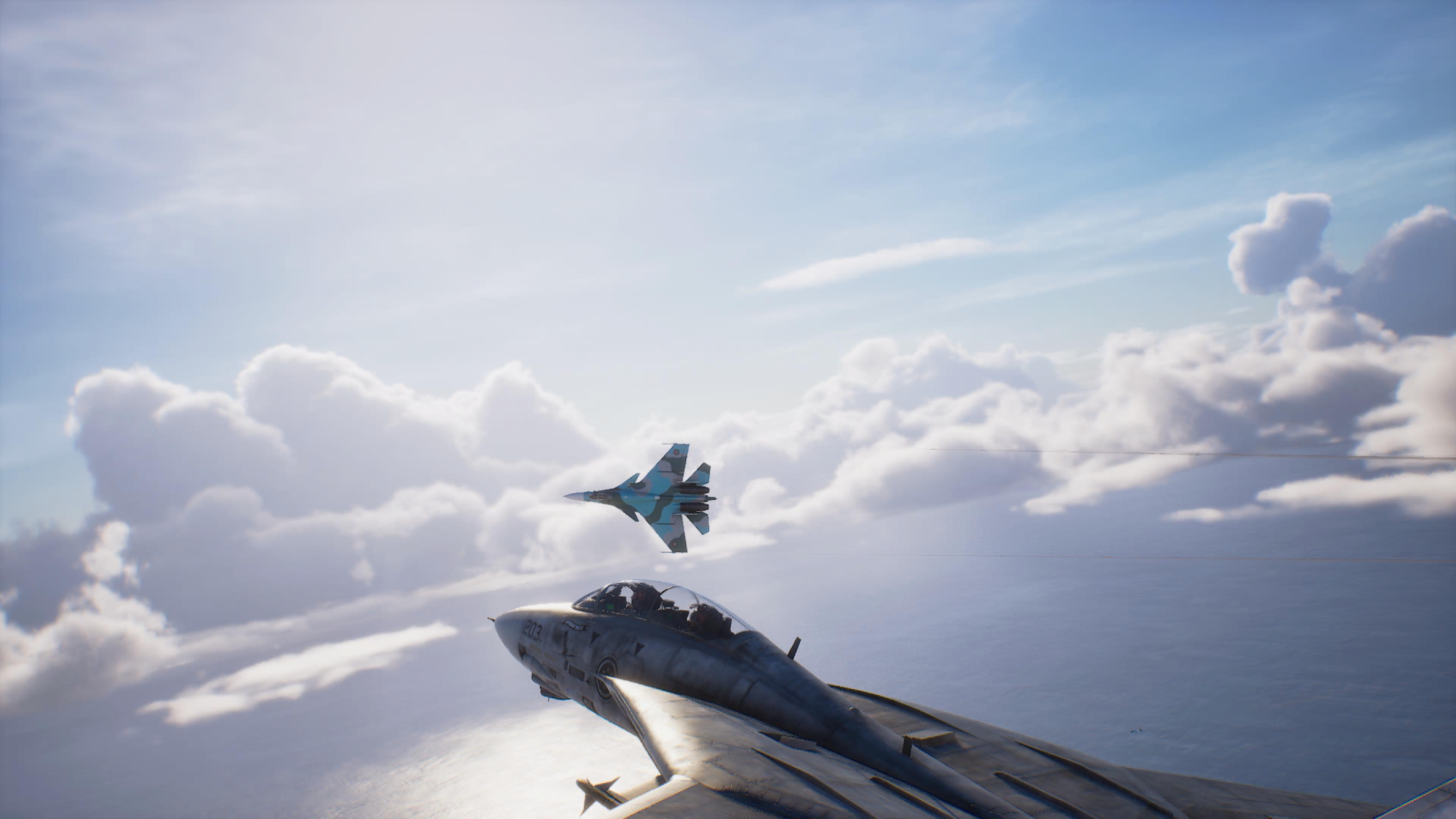 Ett stridsflygplan i blågrön kamouflage svänger över molnen, sett från cockpiten på en annan jaktplan som flyger över havet i Ace Combat 8: Wings of Theve.