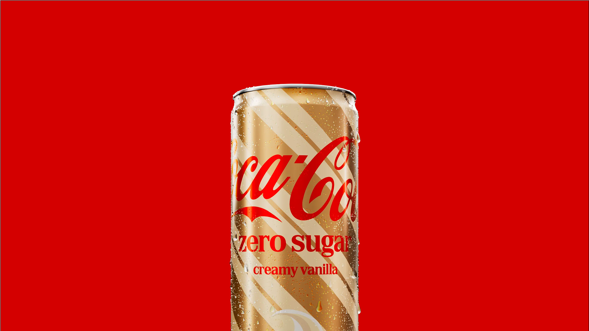 Smal Coca-Cola Zero Sugar-burk i smaken Creamy Vanilla med guld- och vitrandig design och daggdroppar, mot en klarröd bakgrund.