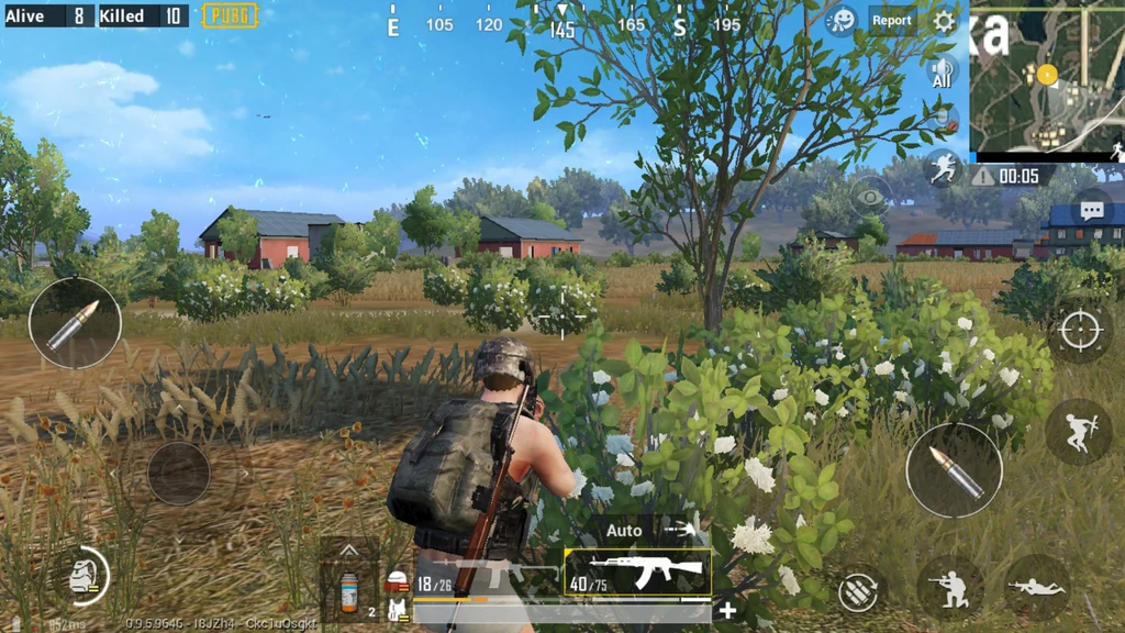 PUBG Mobile: spelare med hjälm och ryggsäck står bakom en blommande buske och siktar med ett automatgevär mot röda hus på ett fält.
