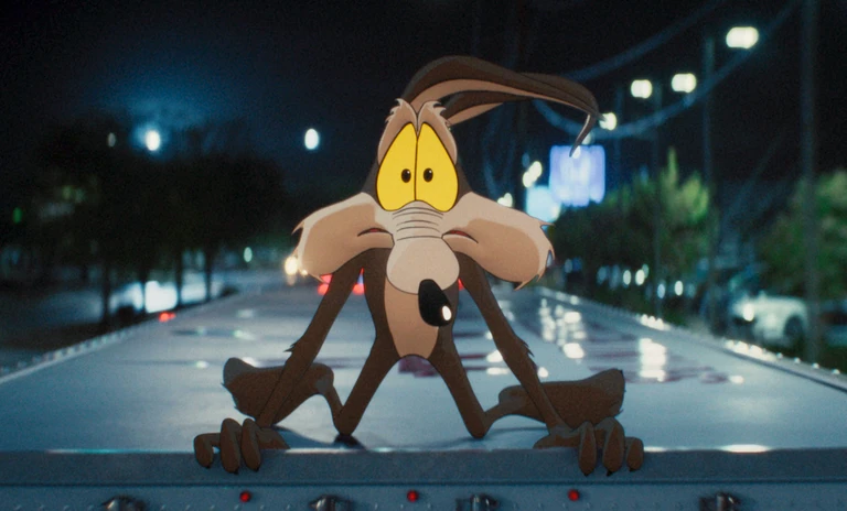 Den tecknade prärievargen Wile E. Coyote sitter med oroliga gula ögon uppe på ett lastbilsflak under en nattlig stadsgata i regn, i filmen Coyote vs Acme.