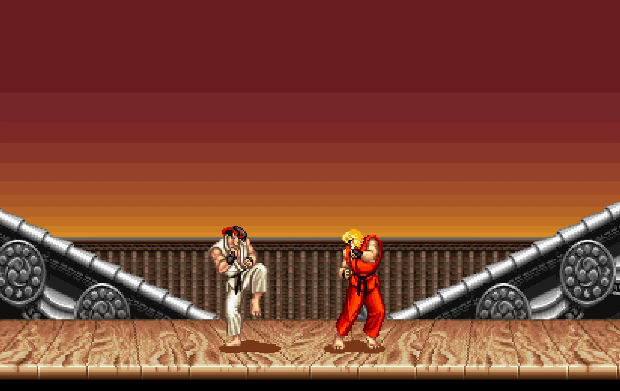 Två kämpar i pixelgrafik står redo att slåss på ett trägolv under en rödorange kvällshimmel, en i vit dräkt och en i röd dräkt med blont hår, i ett Street Fighter-spel.