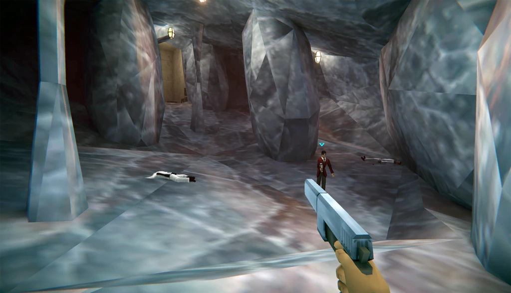 Förstapersonsvy i Agent 64: Spies Never Die. Spelaren siktar med en pistol i en grottkorridor av kantiga grå stenväggar mot en fiende i mörk kostym.