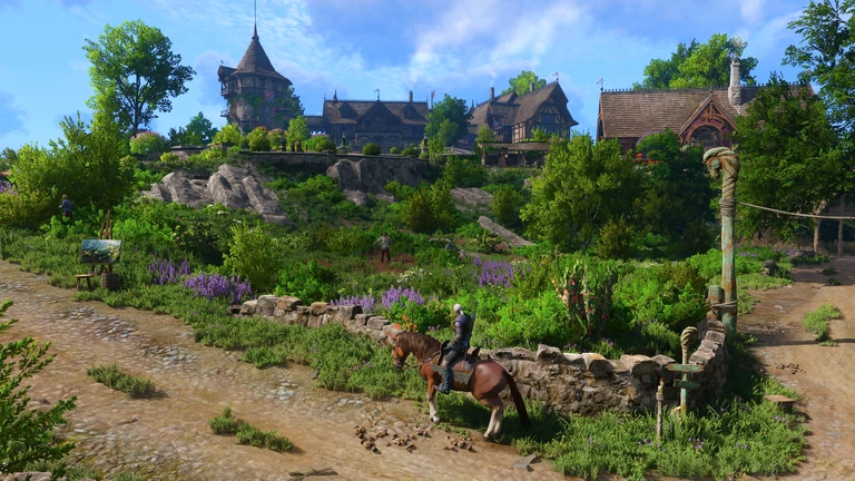 Geralt rider en brun häst längs en stig förbi en stenmur och blommande lavendel, med trähus och ett torn på kullen bakom, i The Witcher 3.