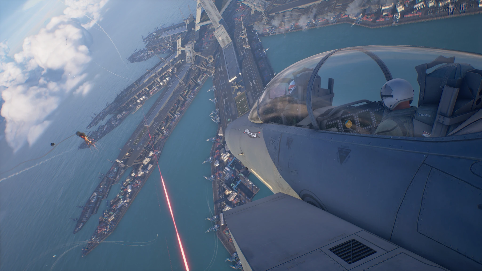 Stridspilot i vit hjälm sedd genom kabinkåpan på ett jaktplan som banar sig över en hamn med örlogsfartyg, medan en röd laserstråle skär över vattnet i Ace Combat 8.