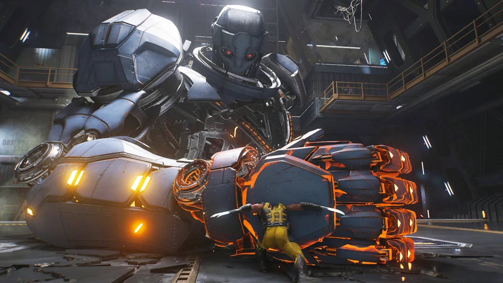Wolverine i gul dräkt stoppar med klorna en gigantisk robotnäve med glödande orange detaljer, medan en enorm Sentinel-liknande robot med röda ögon tornar upp sig i en industrihall.