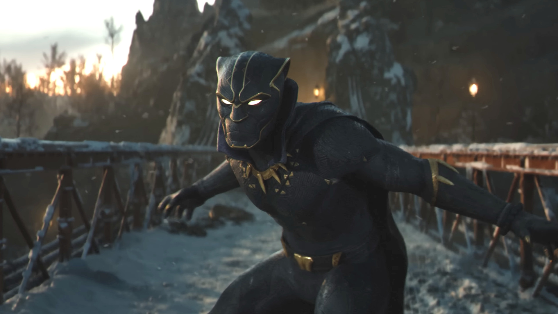 Black Panther i mörk dräkt med gulddetaljer och lysande vita ögon står lätt framåtlutad på en snöig bro i skymningsljus, med bergsväggar i bakgrunden.