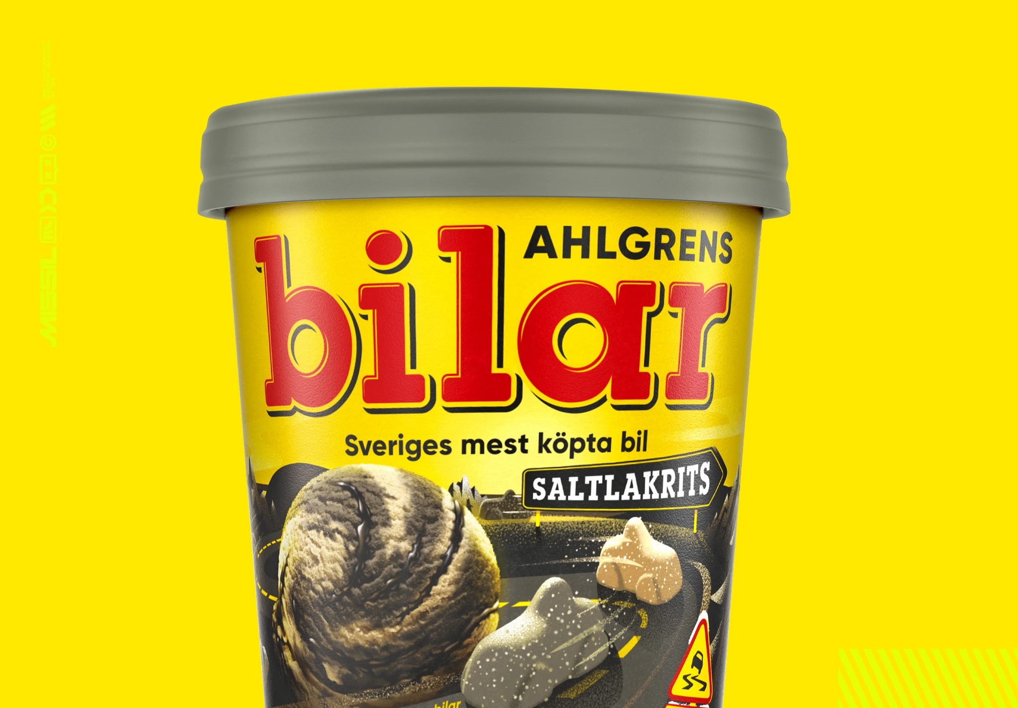 Glassboxen Ahlgrens Bilar med saltlakrits mot gul bakgrund, med en kula mörk glass och två bilformade godisar på en vägbana.