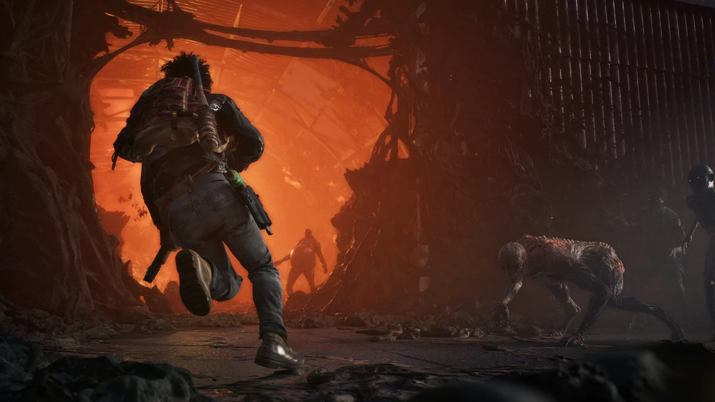 State of Decay 3: En man med ryggsäck springer mot en eldlysande orange öppning i en förstörd byggnad, medan en vanställd best kryper fram mot honom från höger.