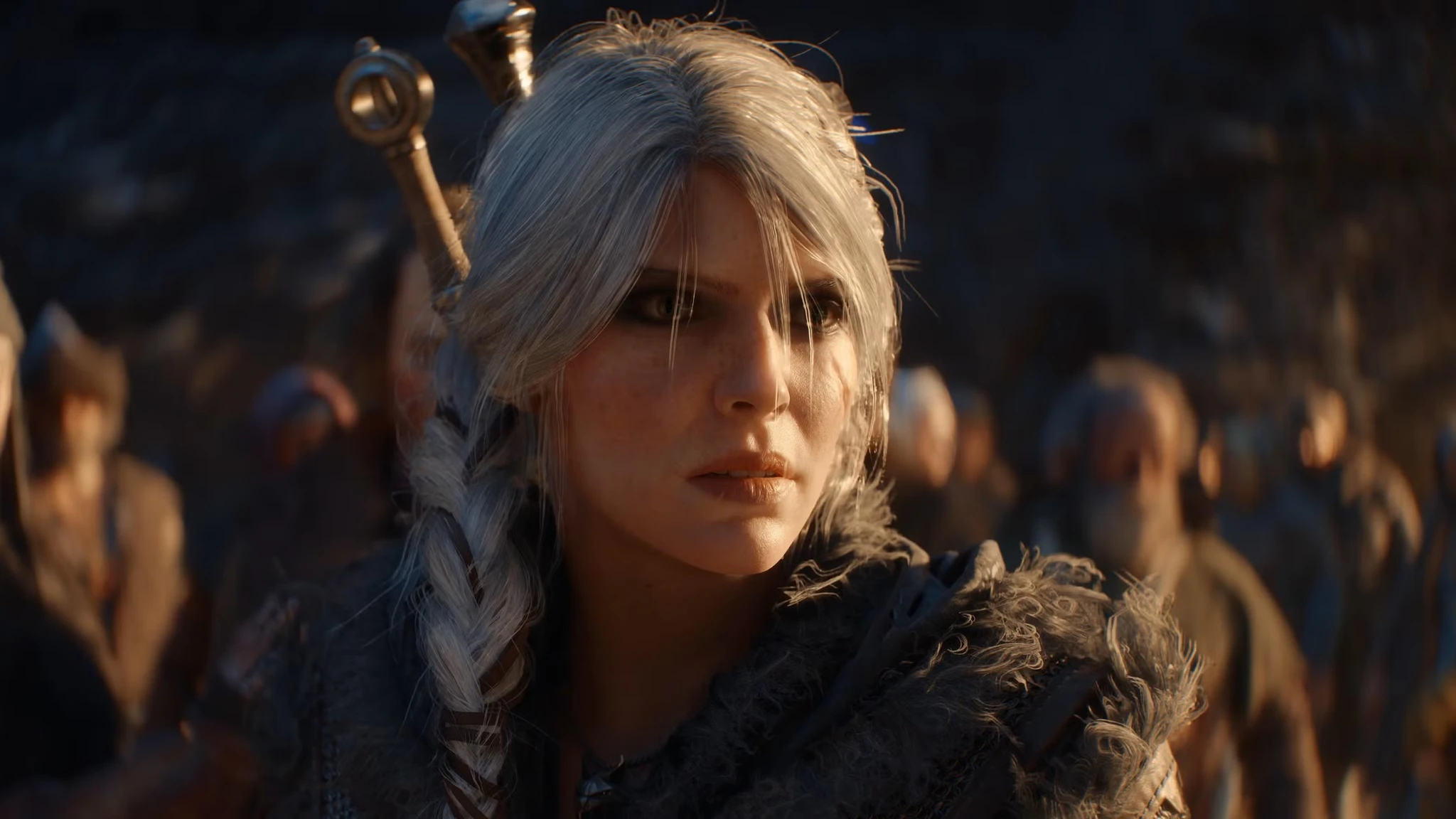 Närbild på en allvarsam kvinna med askgrått hår i fläta och pälskrage, med en folkmassa i suddig bakgrund, i The Witcher IV.