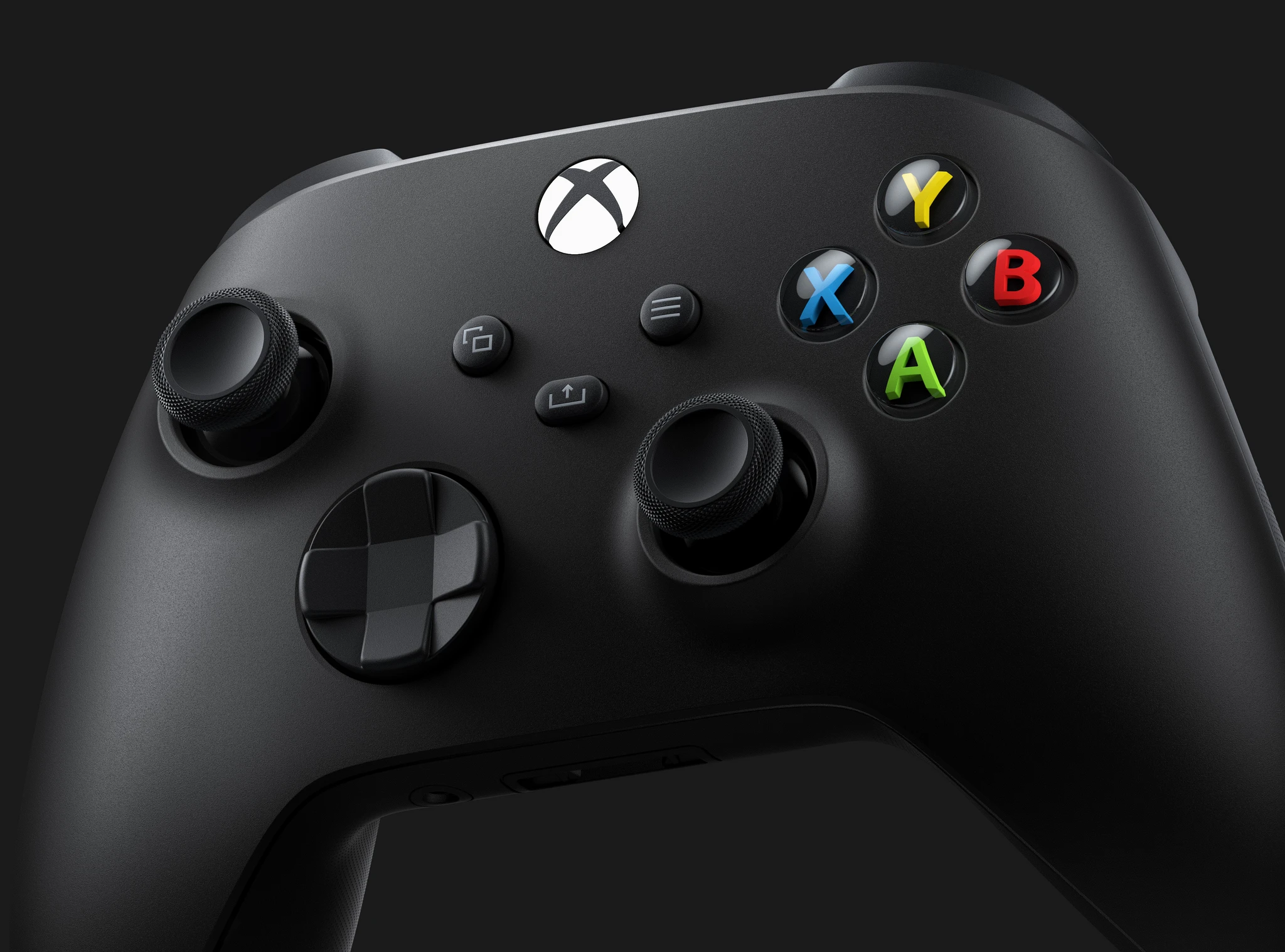 Svart Xbox-handkontroll i närbild med färgade knappar X, Y, B och A, två spakar och ett riktningskors mot mörk bakgrund.