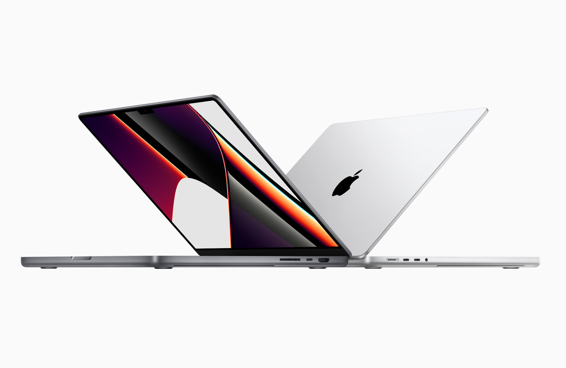 Två Apple Macbook Pro står delvis uppfällda mot varandra, den ena sedd framifrån med en färgstark röd och svart bakgrundsbild på skärmen, den andra bakifrån med silverfärgat lock och Apple-logotyp.