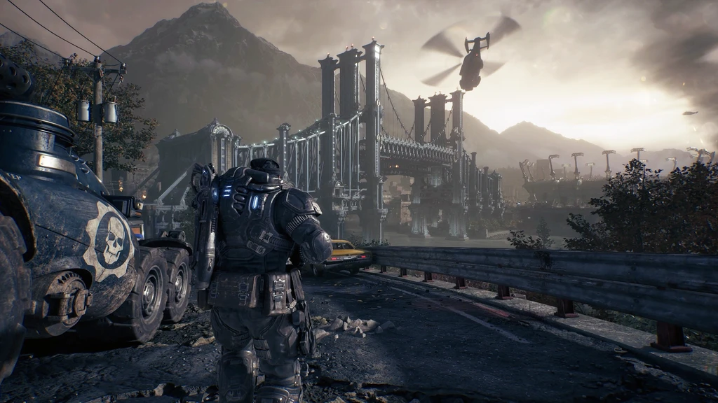 Gears of War: E-Day. En tungt bepansrad soldat sedd bakifrån står på en förstörd väg bredvid ett pansarfordon med dödskallemblem, medan en helikopter flyger över en stor bro i disigt ljus.