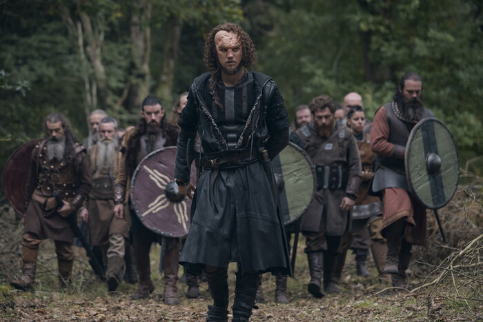 Egil, med ett ärr i pannan och långt lockigt hår, leder en skara skäggiga vikingakrigare med runda sköldar genom en skog i serien Bloodaxe.