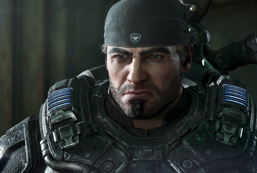 Närbild på en skäggig, butter soldat i tung rustning med blå lysande detaljer och en mörk bandana, i en dunkel miljö från Gears of War: E-Day.