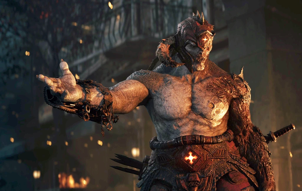 En enorm, muskulös och sönderbränd fiende med glödande ögon sträcker ut handen mot kameran i en mörk, brinnande stadsmiljö i Gears of War: E-Day.