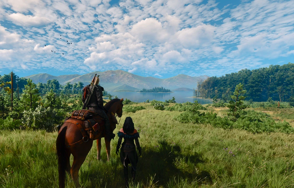 Geralt till häst och en mörkhårig kvinna står i ett soligt, grönt gräsland i The Witcher 3: Wild Hunt Remastered, med en sjö och berg under en molnig himmel.
