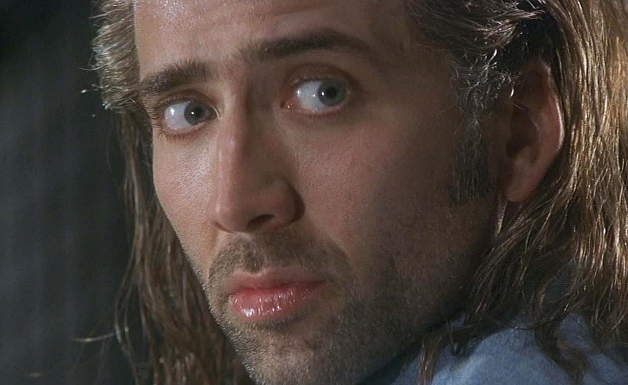 Närbild på en man med långt, svettigt hår och skäggstubb som ser åt sidan med blicken spänd, en filmruta ur Con Air.