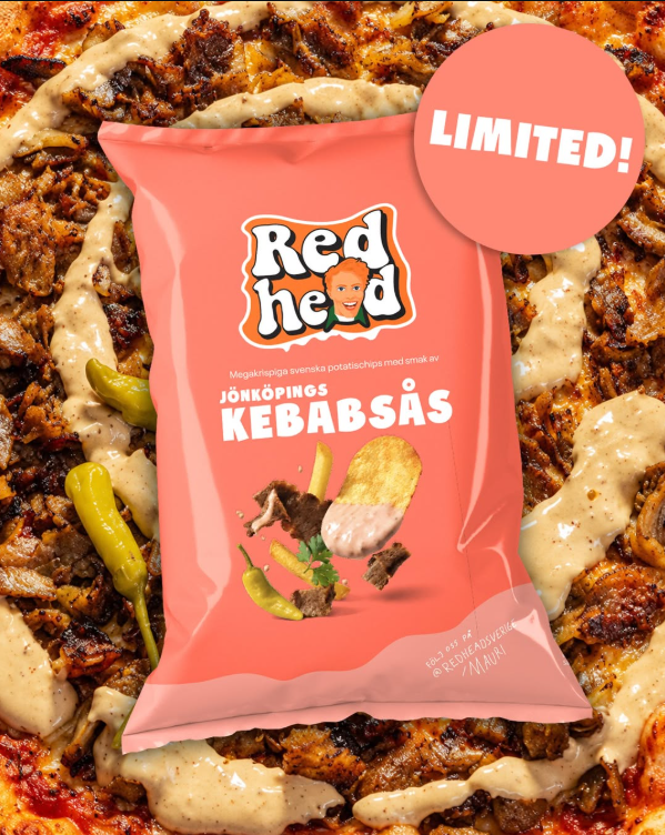 Rosa chipspåse från Redhead med smak av Jönköpings kebabsås, limited edition, liggande över en kebabpizza med sås och pepperoncini.