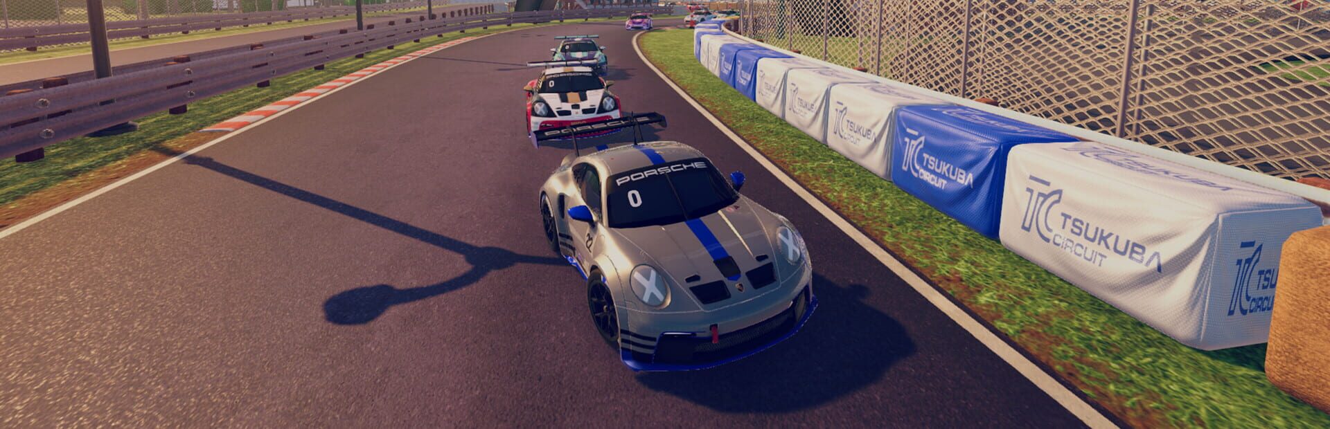 Silvergrå Porsche med blå ränder leder ett fält racerbilar genom en kurva på Tsukuba Circuit i iRacing Arcade, med däckbarriärer längs banan.