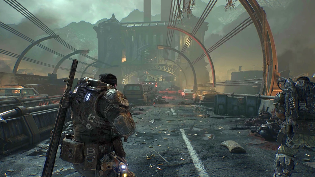 Två tungt bepansrade soldater går över en raserad bro full av vrakbilar och tomhylsor i Gears of War: E-Day, med en förstörd stad i dis framför sig.