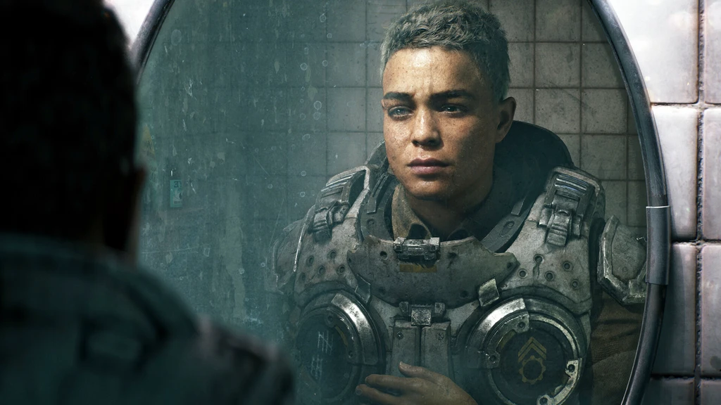 En ung man med kortklippt hår och trött blick betraktar sig själv i en smutsig, kaklad spegel iklädd tung pansarvästs i Gears of War: E-Day.