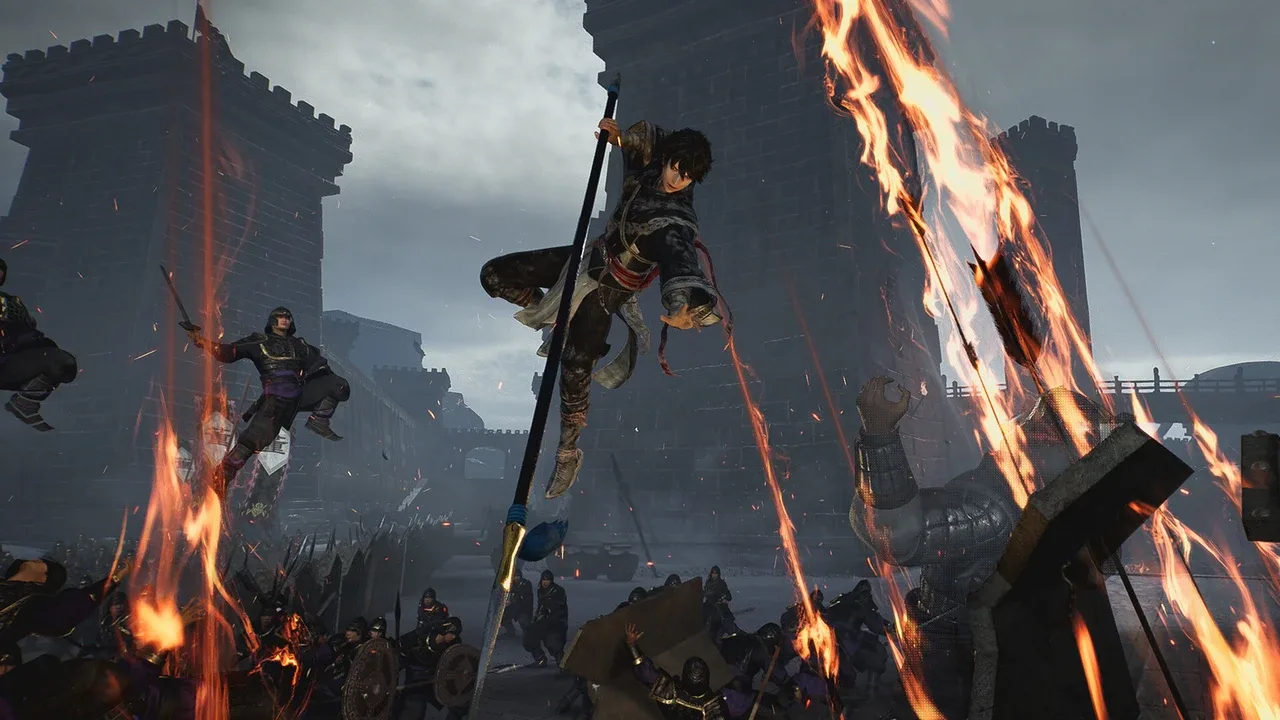 En krigare hoppar högt i luften med ett långt spjut över ett slagfält där eldpilar regnar ner mot soldater framför ett mörkt slott, i ett Dynasty Warriors-spel.