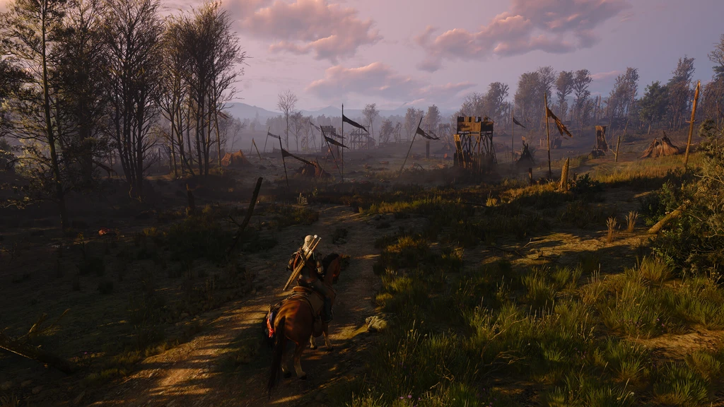 Vitharig ryttare på häst följer en slingrande stig genom ett dimmigt fält mot ett övergivet läger med trasiga flaggor och vakttorn i skymningsljus, i The Witcher 3: Wild Hunt.
