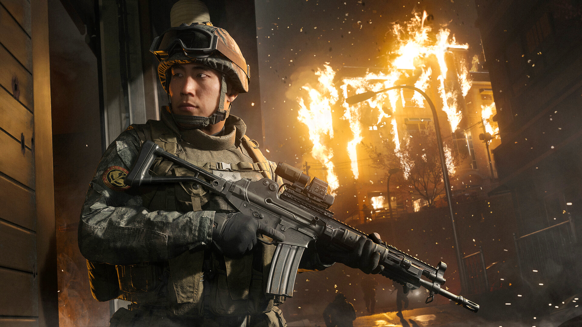 Call of Duty: Modern Warfare 4: en soldat med hjälm, skyddsglasögon och automatkarbin tar skydd vid en husvägg medan en byggnad brinner i bakgrunden.